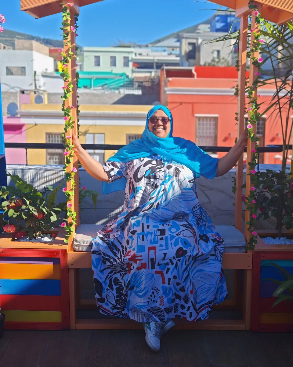 Aalia Ganie smiling on a rooftop terrace above the colourful houses of Bo-Kaap, Cape Town